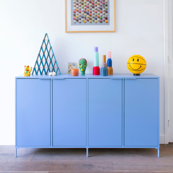 A Sky Blue Type02 Sideboard with four even closed-door sections and slim legs stands colourfully decorated with contrasting, playfully-coloured kids' room objects.