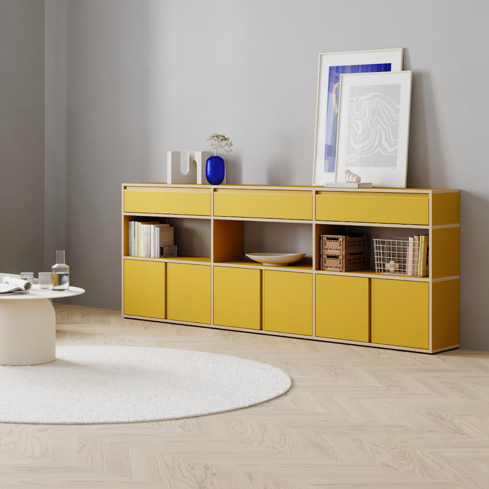 A bright yellow Type01 Sideboard with exposed birch edges with two rows of drawers separated by one row of open display compartments brings a pop of colour to a neutral living room.
