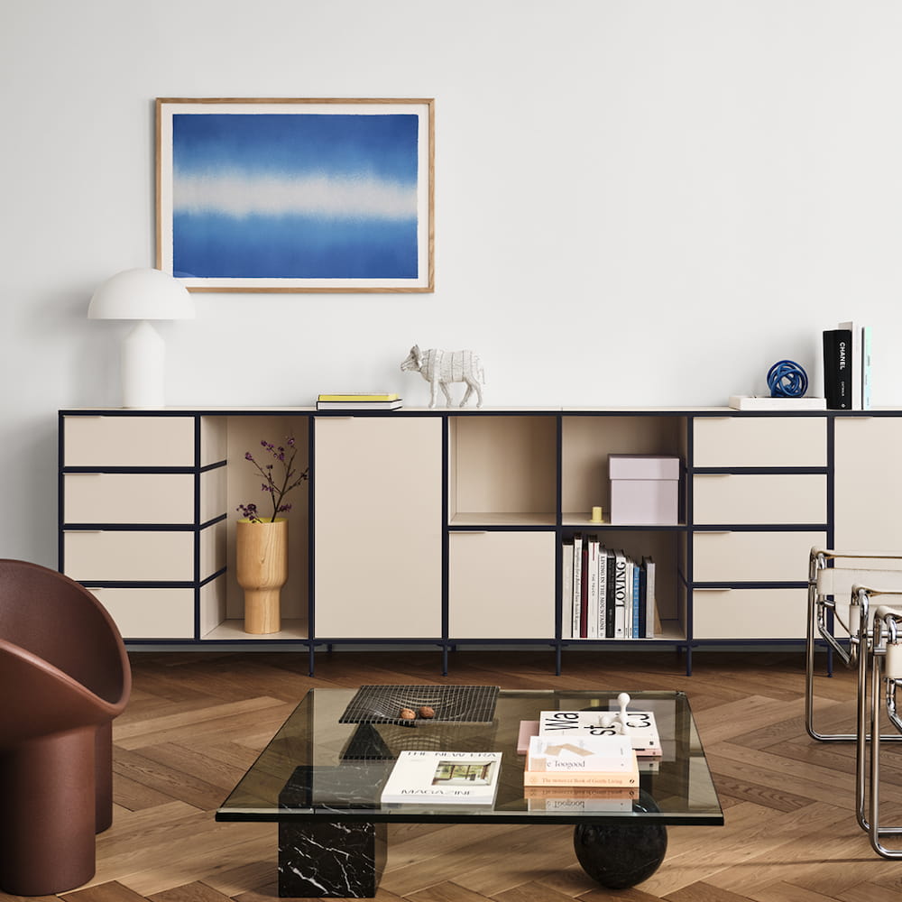 A stylish mixed open and closed section Type02 Sideboard in Sand and Midnight Blue is decorated with assorted objects, books and a bold lamp in a light living room with wood floors.