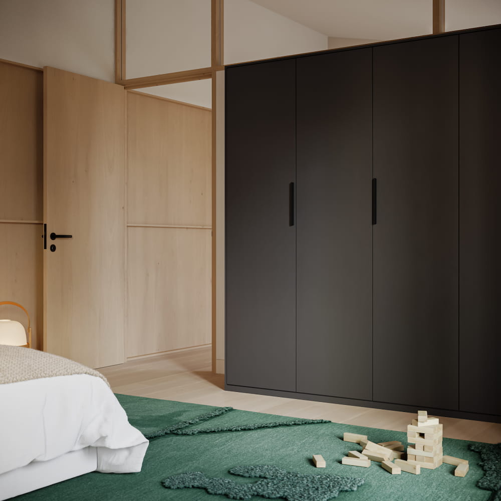 An extra-height Tone Wardrobe in Graphite Grey with added overhead storage and slim doors stands in a bedroom decorated in soft greens and wood tones.